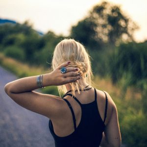 A woman walking down a peaceful path through bushland, gently holding her ponytail, symbolizing trauma healing and reconnecting with nature.
